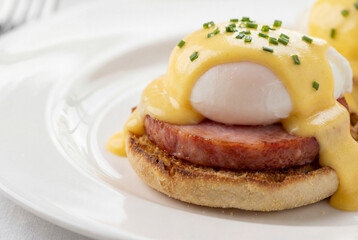 Breakfast eggs benedict with potato pancakes and fried sausage