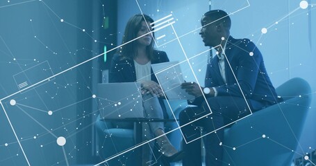 Sitting pair wearing blazers reviewing document in office lounge with laptop and digital overlay