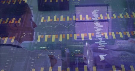 Analyzing female analyst in white shirt studying charts and tapping tablet in office, copy space