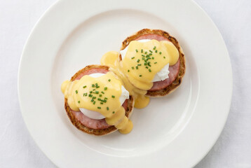 Breakfast eggs benedict with potato pancakes and fried sausage