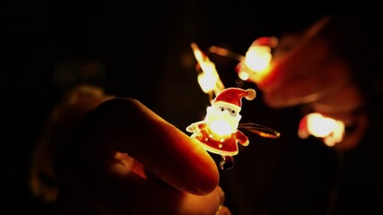 Christmas and New Years garlands in hands. Glowing garlands in womens hands in the dark. A magical, cozy Christmas atmosphere.Decorations and decorations for the winter holidays.  - Powered by Adobe