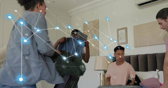Sorting group of five men packing clothing into open suitcase in bedroom, with network overlay
