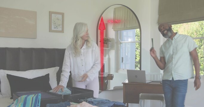Packing senior woman arranging blouse on bed in bedroom, with open suitcase and red AR overlay - Powered by Adobe