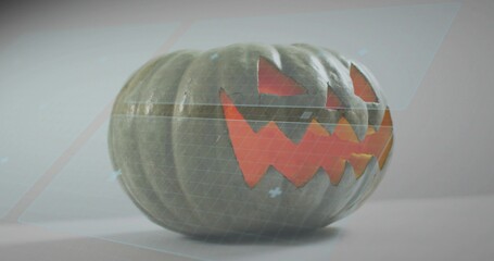 Fototapeta premium Showing carved pumpkin with glowing triangle eyes, jagged mouth on studio table, with hologram grid