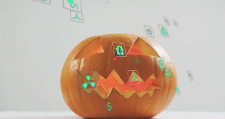 Fototapeta premium Sitting carved pumpkin glowing with internal light on tabletop, projecting green holographic icons