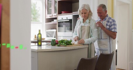 Chopping woman in apron preparing veggies on cutting board in home kitchen, partner holding cloth
