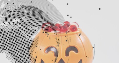 Showing pumpkin bucket holding red candies on white backdrop with halftone overlay, copy space