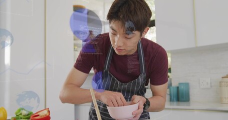 Mixing Korean teen in maroon tee and apron preparing vegetables at modern kitchen, with pink bowl
