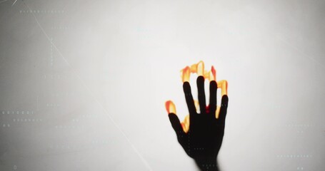 Fototapeta premium Reaching dark hand showing glowing flame fingertips at studio backdrop, cyan code lines, copy space