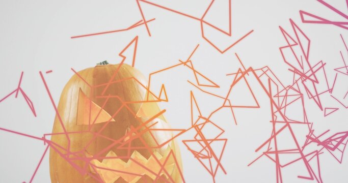 Glowing carved pumpkin emitting warm light at studio with green stem, wireframe shapes, copy space