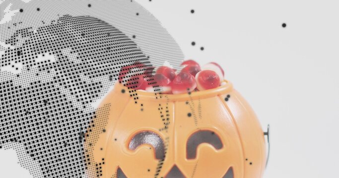 Showing pumpkin bucket holding red candies on white backdrop with halftone overlay, copy space - Powered by Adobe