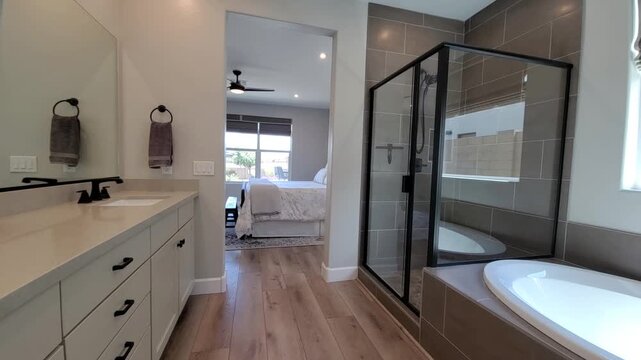 Elegant Master Bath With Natural Lighting, Stylish Bathroom Featuring Glass Enclosure And Wooden Flooring