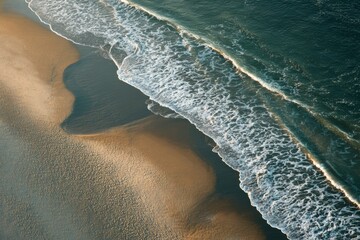 Aerial view of serene beach with gentle waves and sandy shore creating a tranquil coastal landscape at sunset or sunrise
