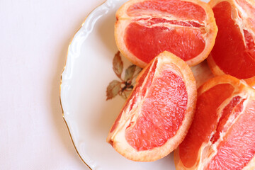 Close-up of cut grapefruit on a white vintage plate and a wood background. Fruit and good nutrition. Grapefruit and sources of vitamins. Grapefruit background and natural food.