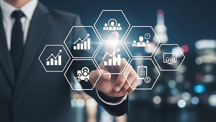 Businessman touches glowing digital interface displaying business analytics and team management tools against a blurred cityscape at night, symbolizing innovation.