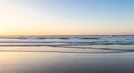 Seascape reflecting soft dawn light on wet sand at a coastal location