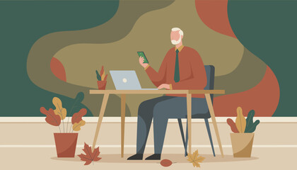 Older businessman uses smartphone and laptop at his desk in a warm autumnal home office