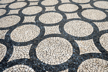 Geometric mosaic design of connected circles made from black and white paving blocks or cobbles in a traditional Portuguese calcada pavement in Porto