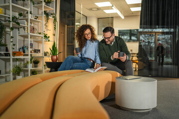 Colleagues discussing and relaxing in modern office lounge