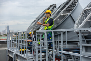 Industrial technician in safety gear inspecting rooftop ventilation systems at a manufacturing...