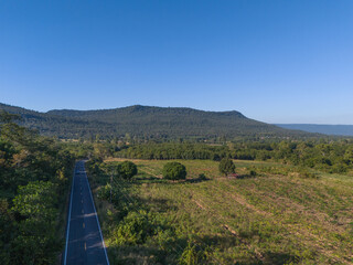 A tranquil rural road stretching straight toward the towering mountains of Dong Luang District in Mukdahan, capturing peaceful nature and stunning landscape scenery.