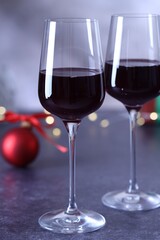 Glasses of red wine and Christmas decor on grey table, closeup