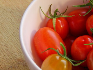 Closeup of bowl of small red tomatoes on wooden surface. Tomatoes in a bowl.