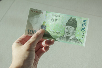A woman's hand holding ten thousand won