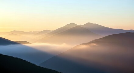 Scenic view of a mountain range with fog and golden light during sunrise or sunset. The image captures a serene and peaceful atmosphere.