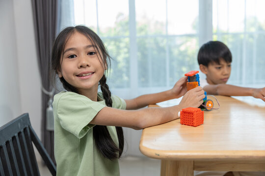 Asian children playing with STEM educational building blocks at home. Concept of learning through play, child development, creativity and early education in fun and safe indoor environment.