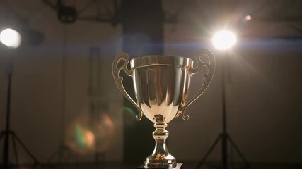 Golden trophy illuminated by spotlight for achievement and success