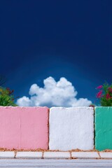 A colorful painted wall with pink, white, and green sections, set against a blue sky with clouds. The image conveys a sense of vibrancy and freshness.