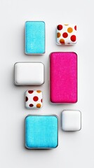 Overhead shot of various cosmetic eyeshadows in different colors and patterns, arranged on a white surface.