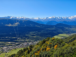 Breathtaking high-angle panoramic view of Mestia village in the Svaneti region of Georgia, surrounded by lush green valleys and the majestic snow-capped Caucasus Mountains under a clear blue sky