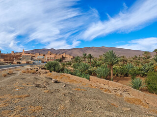 Expansive panorama of a dramatic, rugged canyon landscape in the Moroccan Atlas Mountains, featuring dry red-orange earth and distant, layered mountain ridges