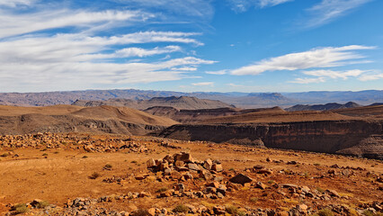 Vast and rugged Moroccan desert mountains panorama with dramatic blue sky and white clouds