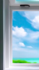 A white window frames a view of a bright blue sky with fluffy white clouds, and a blurred view of the ocean and green vegetation.