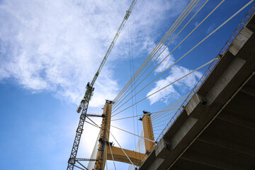 Cable-Stayed Bridge Construction with Tower Crane Under Blue Sky
