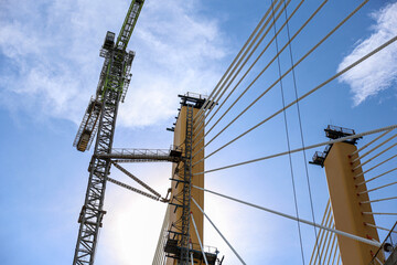 Cable-Stayed Bridge Construction with Tower Crane Under Blue Sky