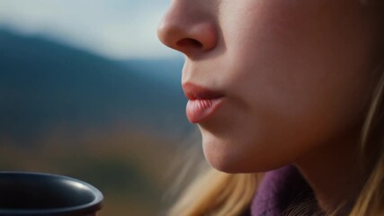 closeup of women taking a sip of hot drink on blurred mountain view spot