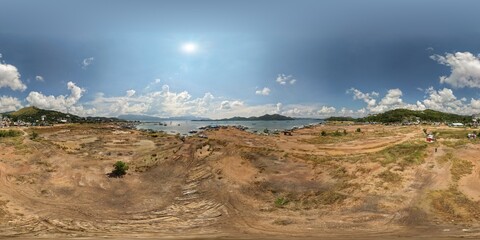 Equirectangular 360 panorama of reclaimed earth coastline with docked boats and Coron town buildings under blue sunny sky