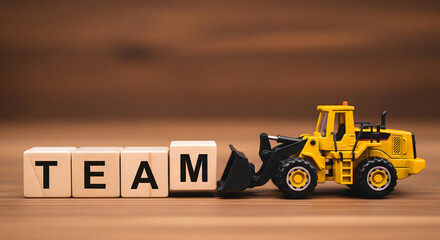 Inspiring team building concept with toy bulldozer pushing letter blocks on a wooden surface for business collaboration, partnership, and teamwork success