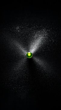 A glowing green orb is surrounded by a spray of water, set against a dark, textured black background. The image is dramatic and abstract.