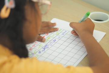 Child writing numbers on a lined chart at a desk
