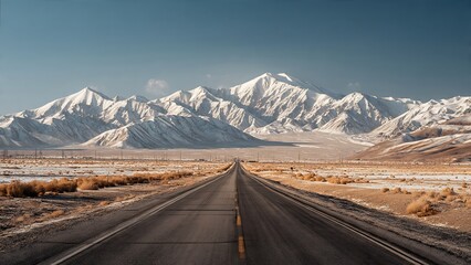 Long Stretch of Highway Across Barren Landscape With Majestic Snow-Capped Mountains