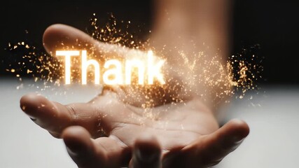 Close up of a human hand opening in slow motion to reveal glowing "Thank You" text with magical particles for appreciation concept and heartfelt message