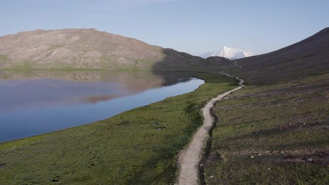 Morning view of Sheosar Lake beside a winding trail, with Nanga Parbat visible in the distance. Deosai, Pakistan