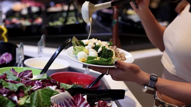 Woman Pouring Salad Dressing at Fresh Vegetable Buffet Bar