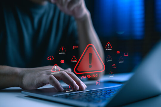 Cybersecurity warning alert on laptop, hacker or IT specialist facing data breach risk, cyber attack or system error. Digital threat concept in dark environment for security awareness.