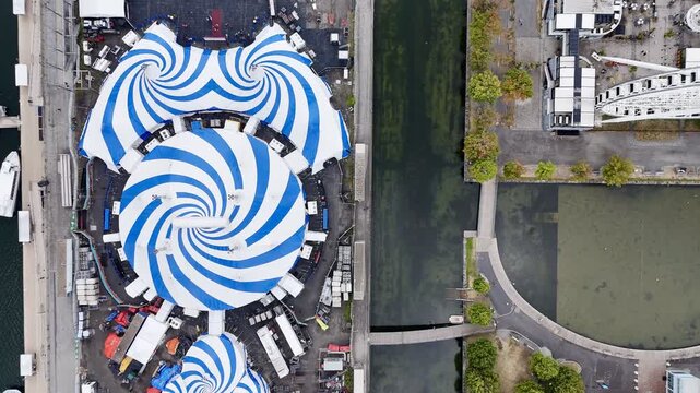 24th of August 2025 drone flight above the Cirque du Soleil blue-white tent at Montreal Old Port with city skyline in background. g.